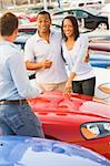 Young couple discussing new car with salesman on lot