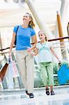 Mother and daughter in shopping mall carrying bags