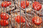 Meat with tomatoes on a lattice of a grill