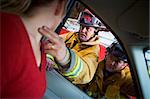 Firefighters helping an injured woman in a car