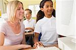 Teacher and schoolgirl studying in front of a school computer