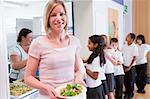 Teacher holding plate of lunch in school cafeteria