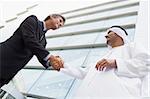 A Middle Eastern businessman shaking hands with a Caucasian busi