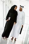 A Middle Eastern businessman and businesswoman walking down a co