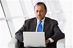 Businessman working on laptop in office lobby