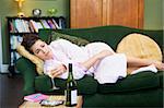 A young woman lying on her couch drinking wine