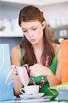 A young woman sitting in a cafe looking sadly into her purse