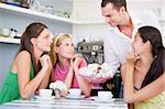 A cafe waiter offers young women teacakes