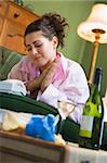 A young woman in her pyjamas drinking wine and watching her tele