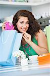 A young woman with shopping bags sitting in a cafe