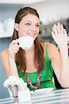 A young woman sitting in a cafe drinking tea and waving
