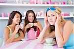 Two young women enjoying a tea party while one sits apart wearin