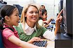 Teacher helping kindergarten children learn how to use computers