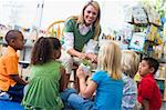 Kindergarten teacher and children looking at seedling in library