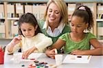 Kindergarten teacher sitting with students in art class,