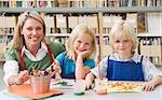 Kindergarten teacher sitting with students in art class