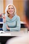 Mature female student raising hand in class