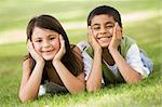 Two children relaxing in park looking to camera