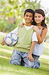 Children playing football in park looking to camera