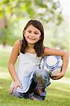Girl in park holding football looking to  camera
