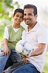 Father and son playing football in park