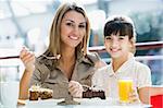 Mother and daughter eating cake in cafe together