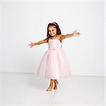 Cute little hispanic girl wearing pink dress dancing.