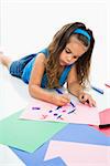 Young latino girl coloring on construction paper.