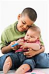 Young latino boy holding baby brother on lap.