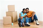 African American male and female couple sitting on floor next to moving boxes.