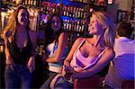 Three young women enjoying drinks together at a nightclub