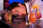 Drunk young man resting head on bar counter