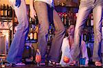 Barman gaping at three young women dancing on bar counter