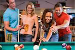 Young man teaching a young woman to play pool