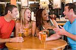 Group of young friends drinking and laughing in a bar