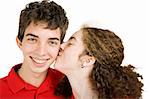 Teen boy getting a kiss on the cheek from his girlfriend.  Isolated on white.