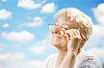 Portrait of the laughing elderly woman with glasses against the sky