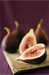 still life three whole figs and one sliced on a wooden cutting board