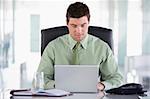 Businessman sitting in office with personal organizer and laptop