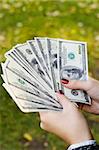 young woman counting roll of hundred dollar bills