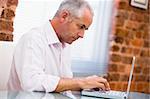 Businessman sitting in office typing on laptop