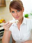 Beautiful woman in kitchen eating using chopsticks