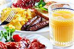 plate of wholesome breakfast with scrambled eggs, bacon, orange juice, and toast with jam.