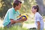 Man and young boy outdoors with soccer ball smiling