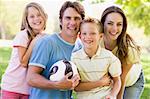 Family standing outdoors holding volleyball smiling