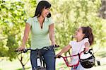 Woman and young girl on bikes outdoors smiling