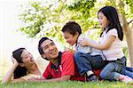 Family lying outdoors being playful and smiling