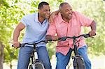 Two men on bikes outdoors smiling