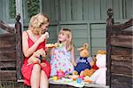 Woman and young girl in shed playing tea and smiling