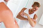 Man in bathroom applying lotion and smiling